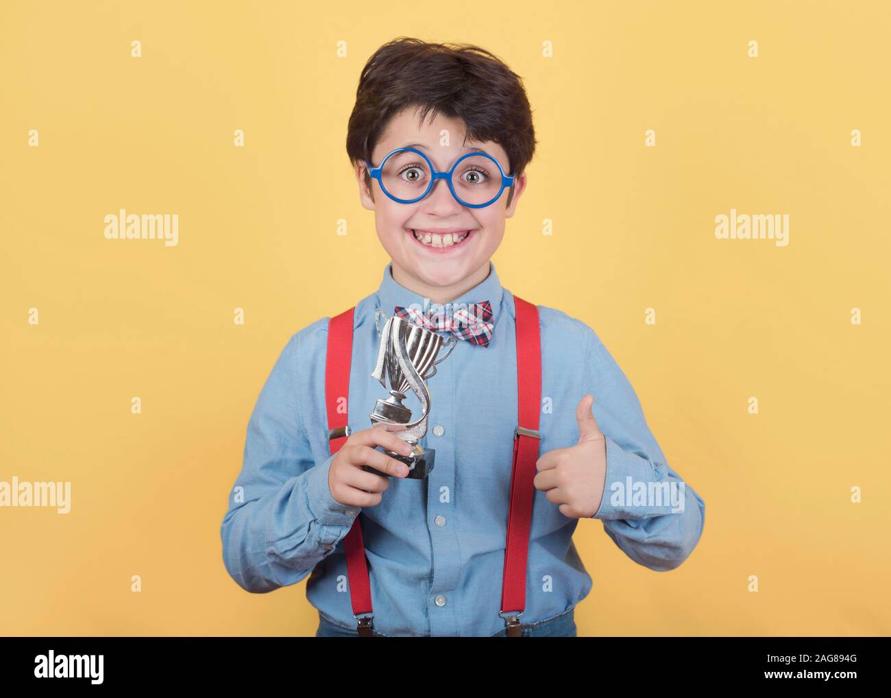 Happy boy with winning cup on yellow background Stock Photo