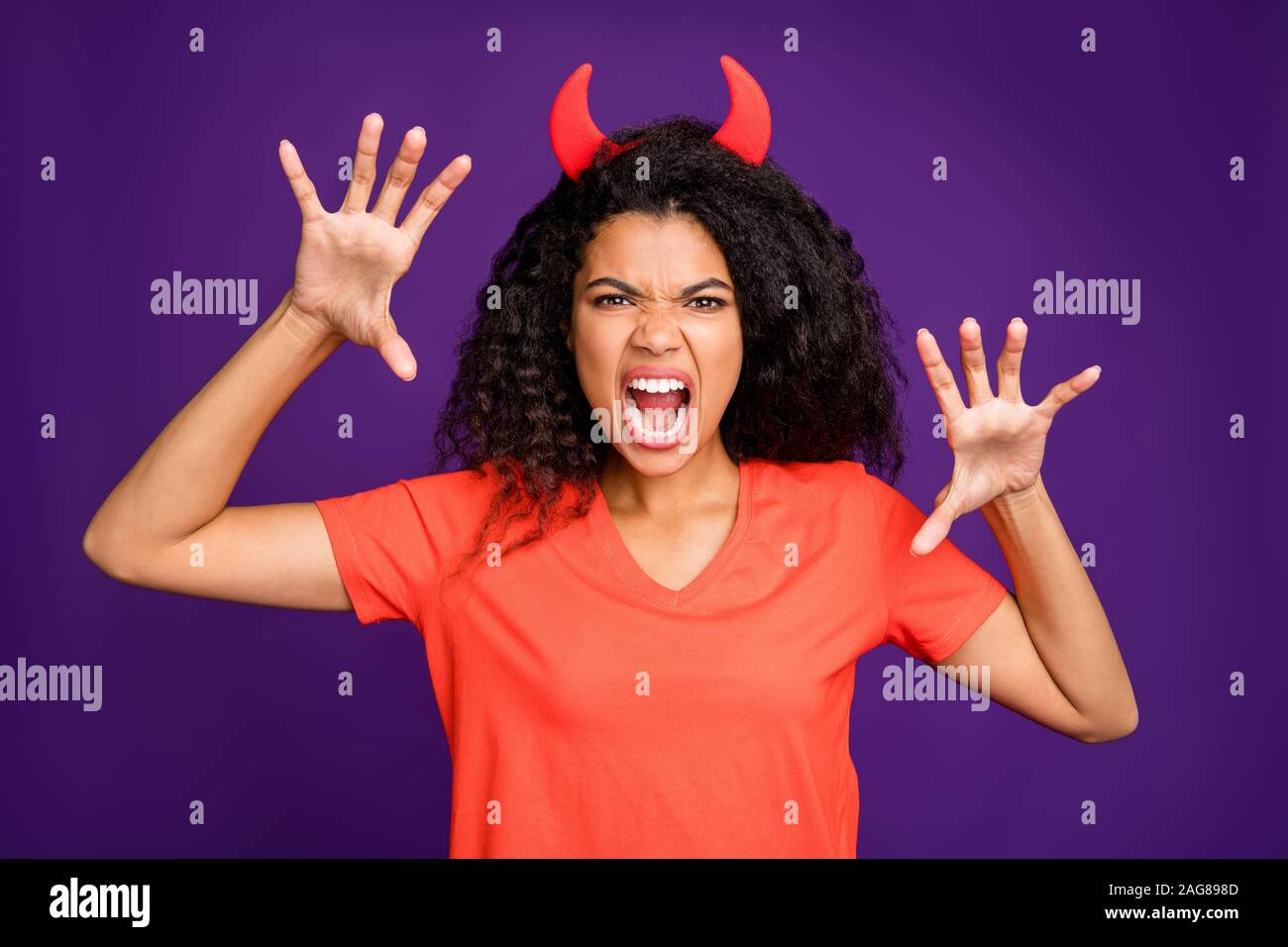 Photof of horrible terrifying mad insane occultist spooky attempting to frighten you with her frightful grimace on face roaring loudly in orange t Stock Photo