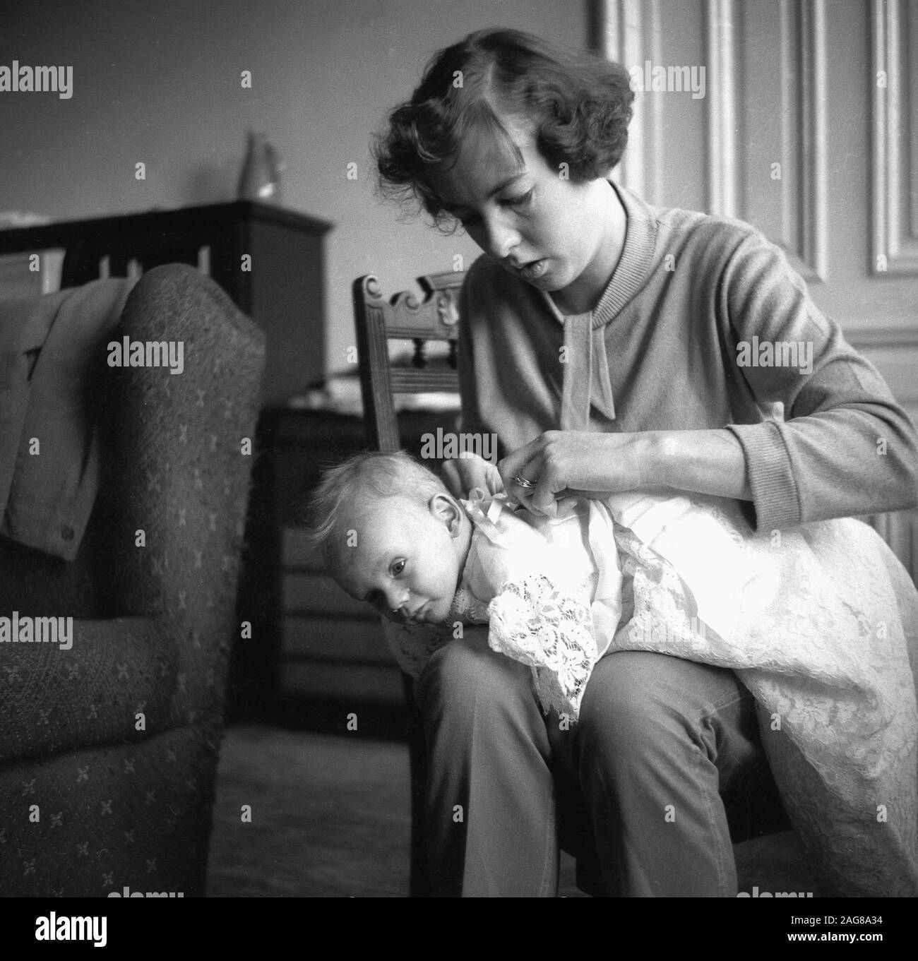 1950s, historical, inside a front room, sitting on a chair, a young