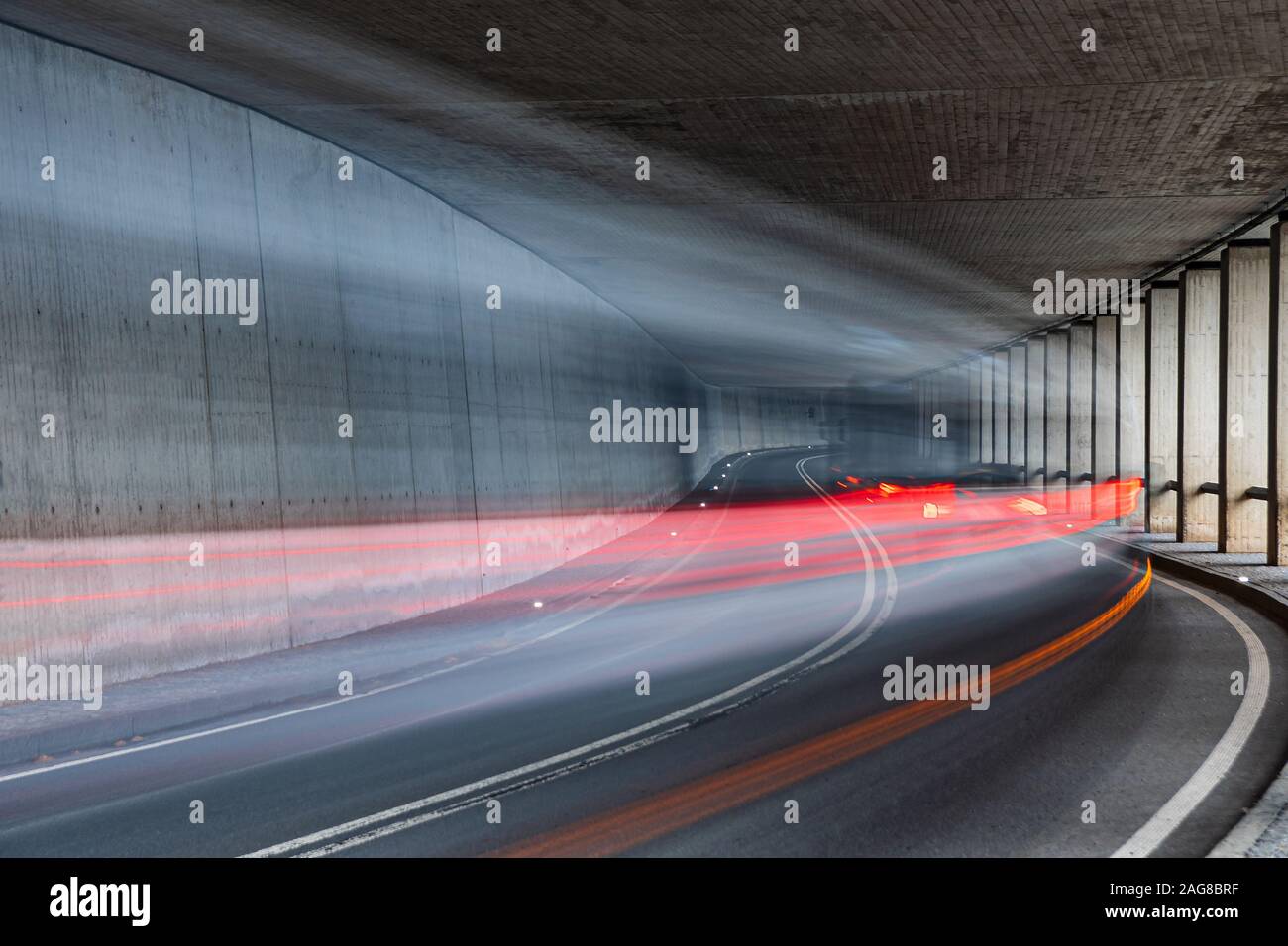 Blurry car with red rear lights driving fast through the tunnel - Long exposure Stock Photo