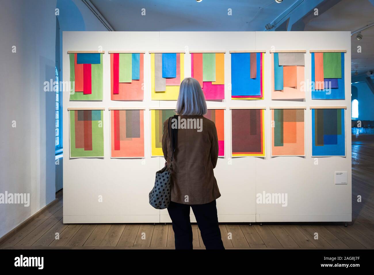 Woman colour, rear view of a middle aged woman looking at a colourful art exhibition (Is This Colour?), Rundetaarn, central Copenhagen, Denmark. Stock Photo