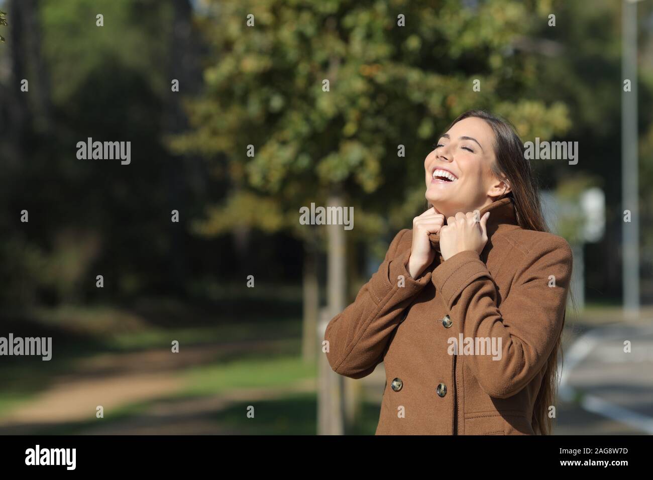 Happy woman warmly clothed in winter breathing fresh air standing in a park Stock Photo