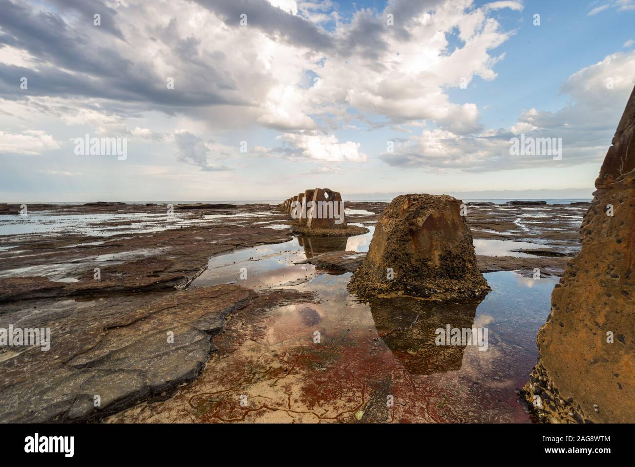 Beautiful shot of a brown rock formation surrounded by the ocean water under the cloudy sky Stock Photo