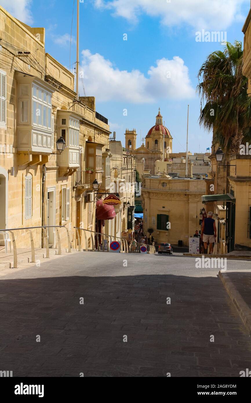 Victoria, Gozo, Malta - September 10, 2016: Street scene in Victoria (Rabat) on Gozo Island, Malta, with St. George's Basilica in the background. Stock Photo