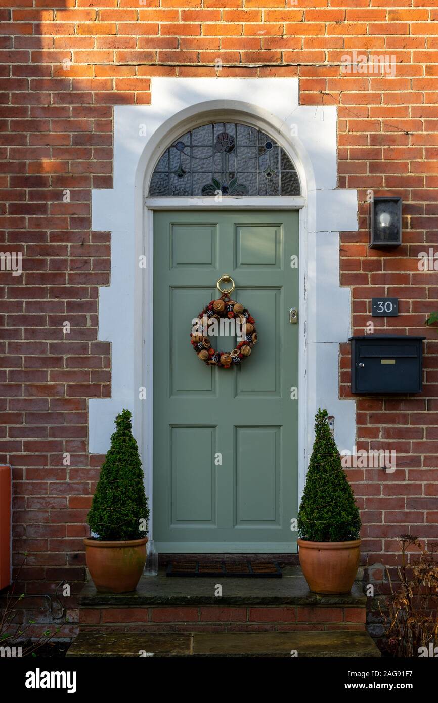 An English Brick cottage door with a Christmas wreath hanging from the front door Stock Photo