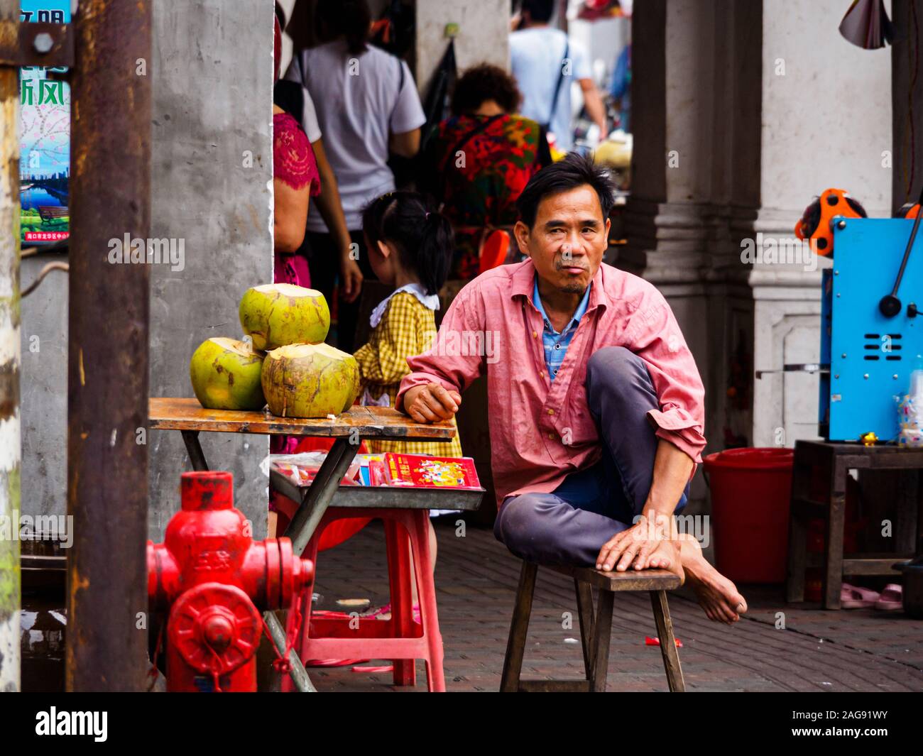 HAIKOU, HAINAN, CHINA - MAR 2 2019 - A street vendor selling fresh coconuts containing coconut water, a popular tropical beverage. Stock Photo