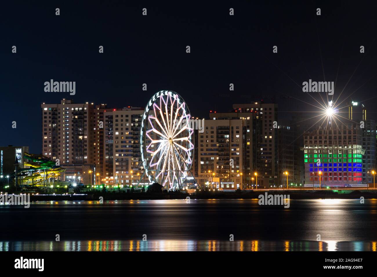 Cityscape with a Ferris wheel and a lot of illuminated buildings ...