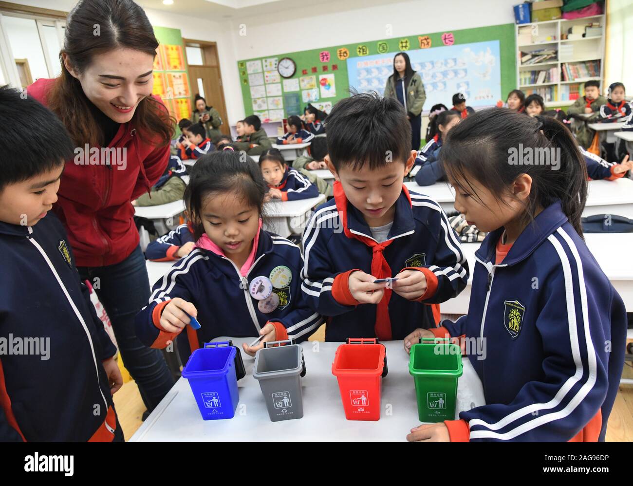 (191218) -- QINGDAO, Dec. 18, 2019 (Xinhua) -- A volunteer administers an amusing game on garbage classification for pupils at the Juyuan Primary School in Qingdao City, east China's Shandong Province, Dec. 18, 2019. Youth volunteers for social service from the Qingdao Zhanqiao Bookstore launched a scientific information outreach program at the Juyuan Primary School Wednesday. Through video clips, knowledge contests, short dramas and amusing games, the volunteers attempted to help the pupils better understand the necessity of garbage classification as well as the importance of environmental an Stock Photo