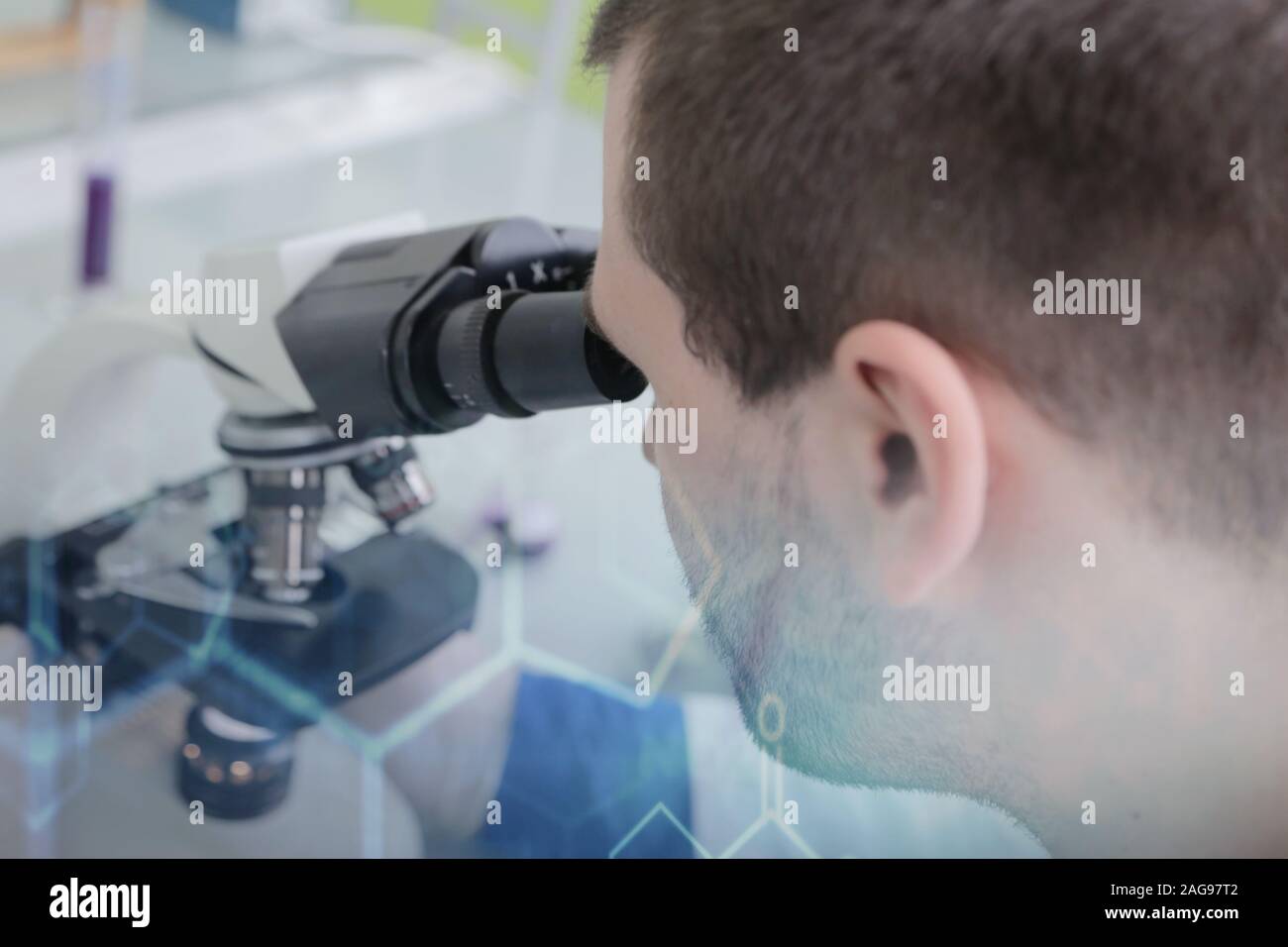 Young male male scientist looking through a microscope in a laboratory ...
