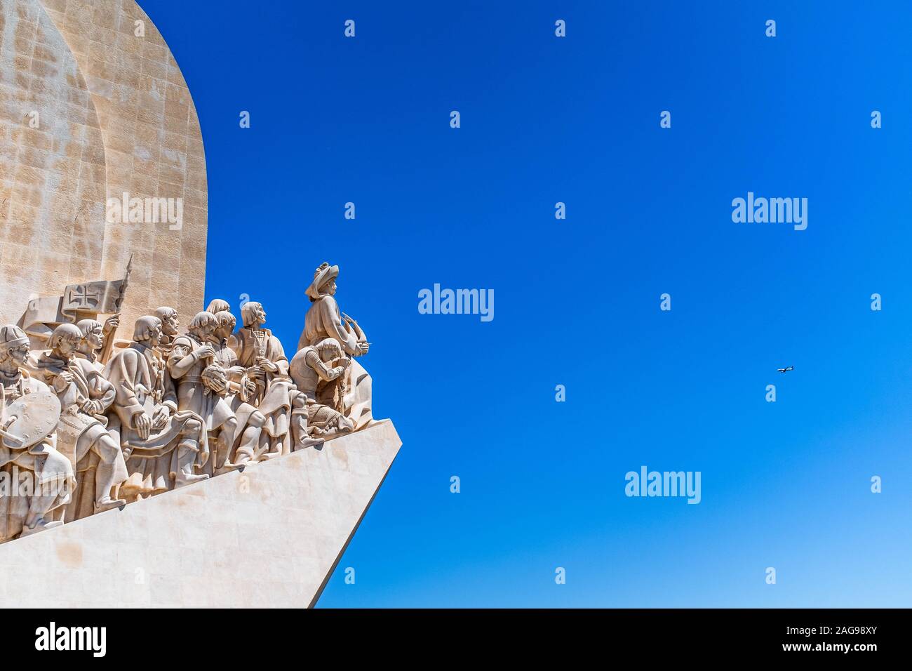 Fragment of Monument to the Discoveries on a blue sky background with a plane visible on a distance. Stock Photo
