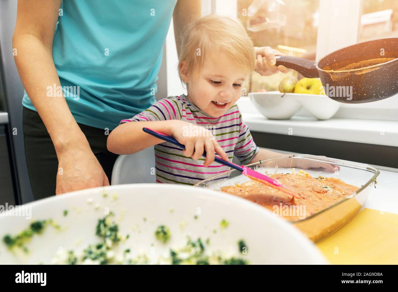 mother and daughter cooking vegetarian lasagne together in home kitchen Stock Photo