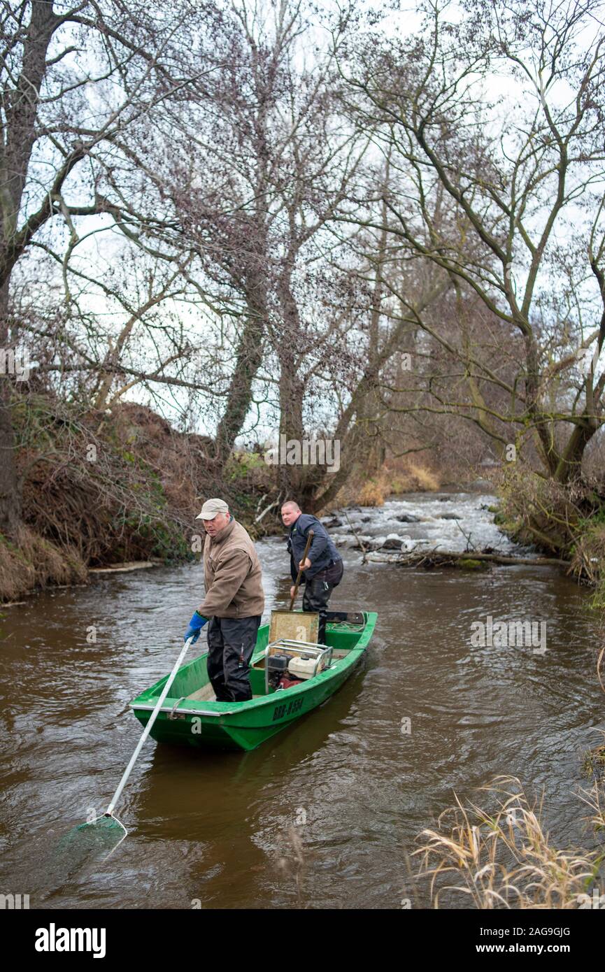 Nutha, Germany. 18th Dec, 2019. Robert Frenzel (l) and Jens Windheuser (r) from the Institute for Inland Fisheries in Potsdam travel the Nuthe downstream in a boat. Fishermen shall carry out a trial fishery in the waters to catch and study spawning salmon and sea trout in order to verify their return. In the Nuthe a total of 143500 young salmon and 90300 sea trout hatchlings have been released so far. The fish then migrate to the Atlantic and return to spawn after a few years. Credit: Klaus-Dietmar Gabbert/dpa-Zentralbild/ZB/dpa/Alamy Live News Stock Photo