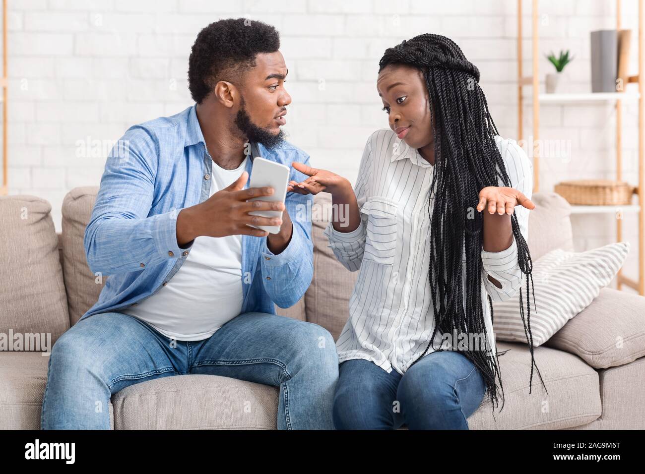 Jealous Boyfriend Showing His Cheating Girlfriend Her Phone, Demanding Explanation Stock Photo