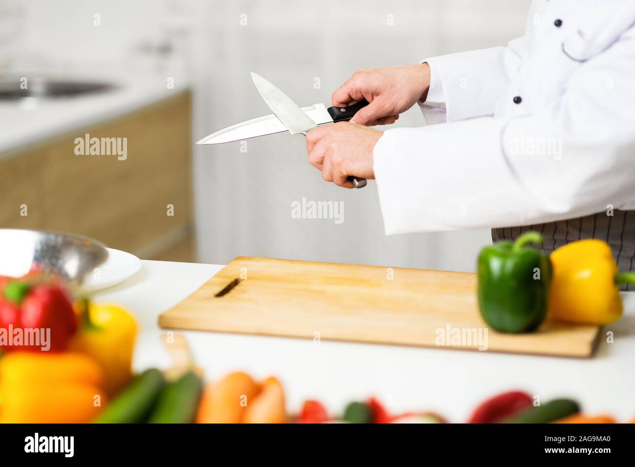 Unrecognizable Chef Man Sharpening Knives Working In Kitchen Indoor, Cropped Stock Photo
