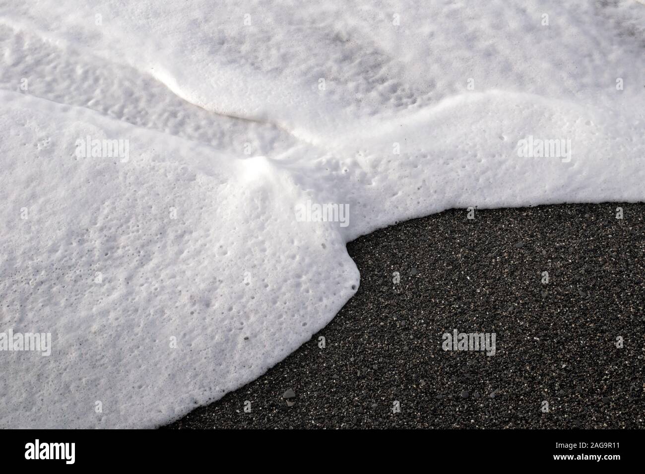 White sea foam on the beach gravel caused by rough sea and high wind Stock Photo