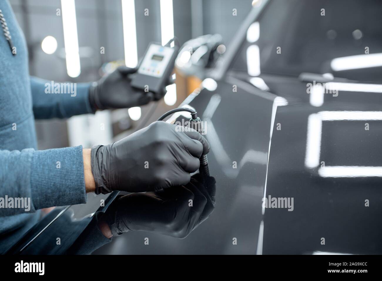 Inspector measuring paint cover thickness of the car body at the