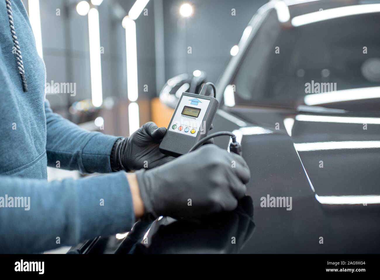 Inspector measuring paint cover thickness of the car body at the