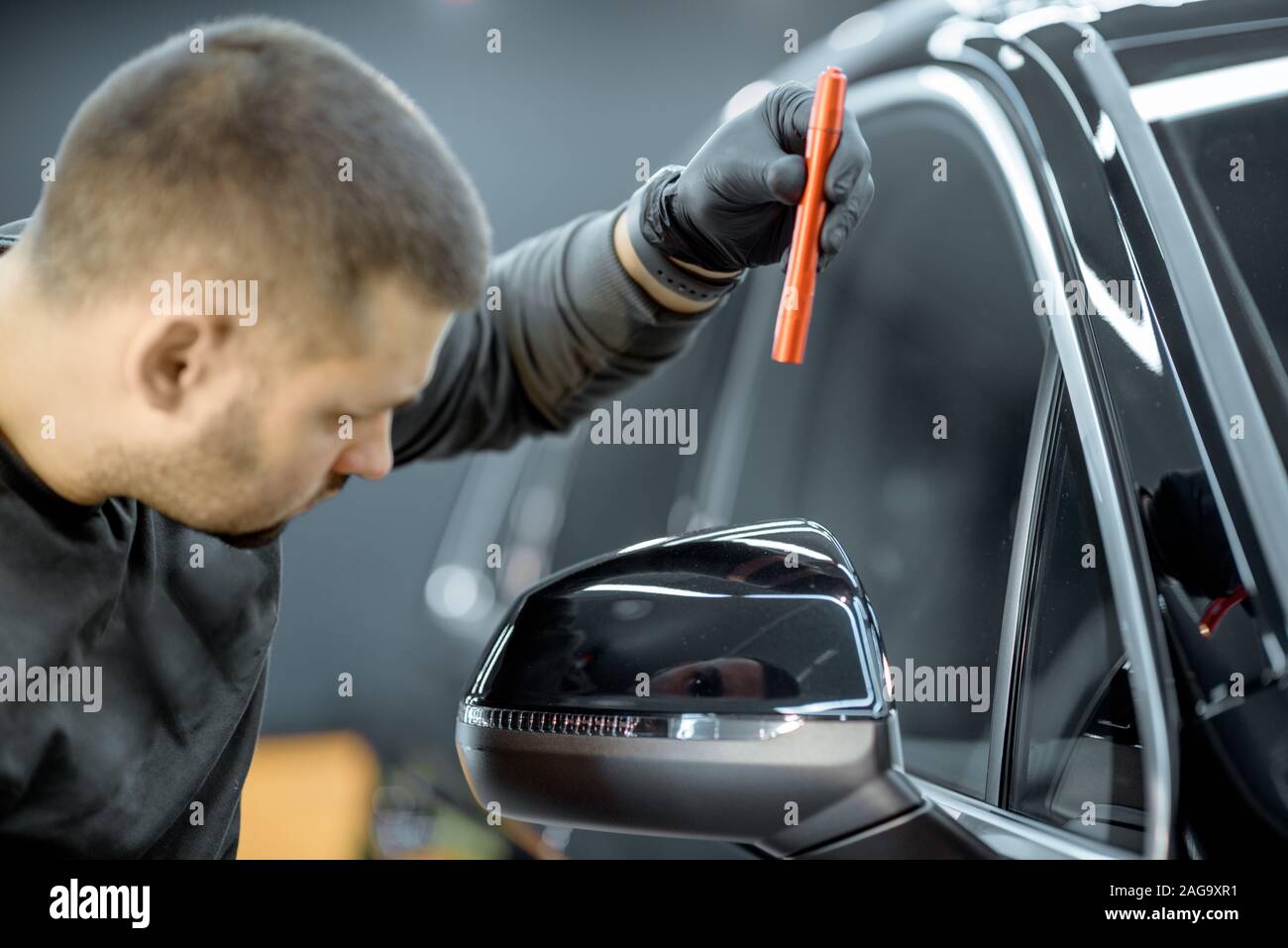 Worker examining vehicle body for scratches and damages backliting by a