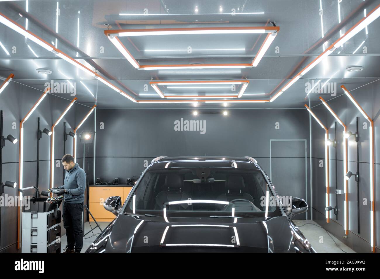 Car service worker preparing for vehicle body detailing at the modern automotive service box. Wide view with copy space Stock Photo