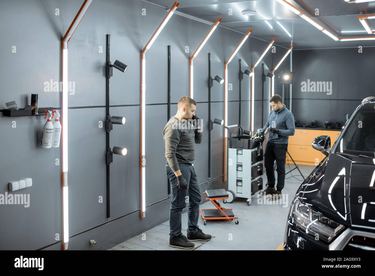 Car service workers preparing for vehicle body detailing at the modern automotive service box Stock Photo