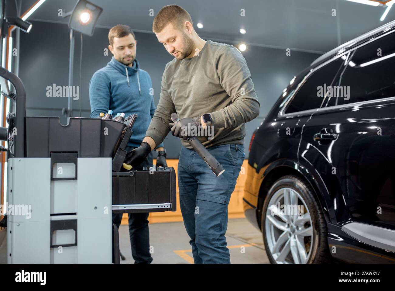 Car service workers preparing for vehicle body detailing at the modern automotive service box Stock Photo