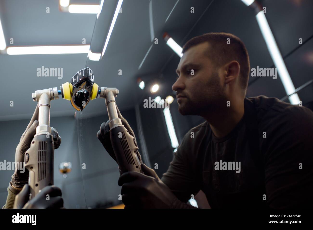 Car service worker polishing vehicle door handle with special wax from