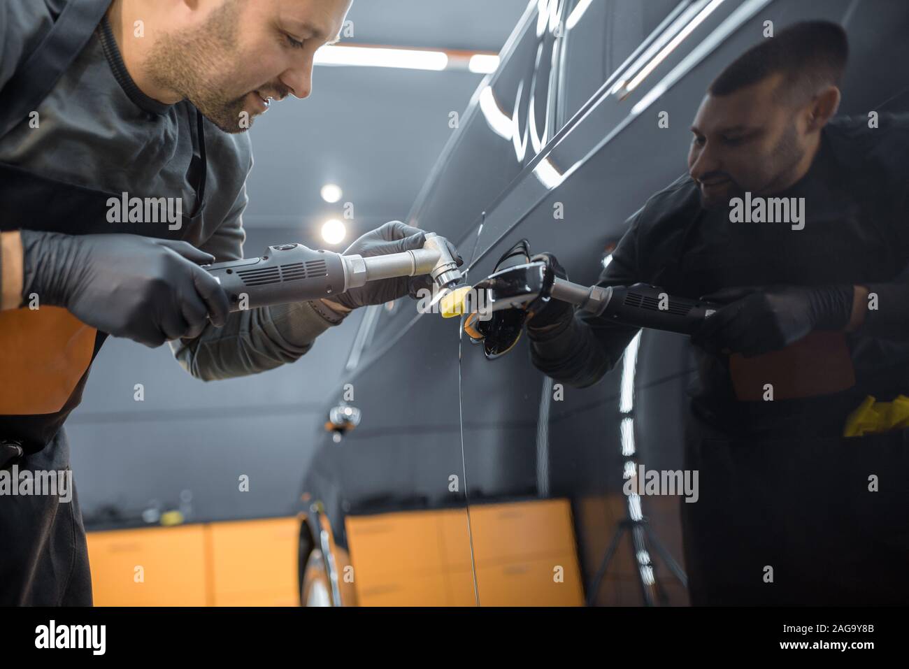 Car service worker polishing vehicle door handle with special wax from