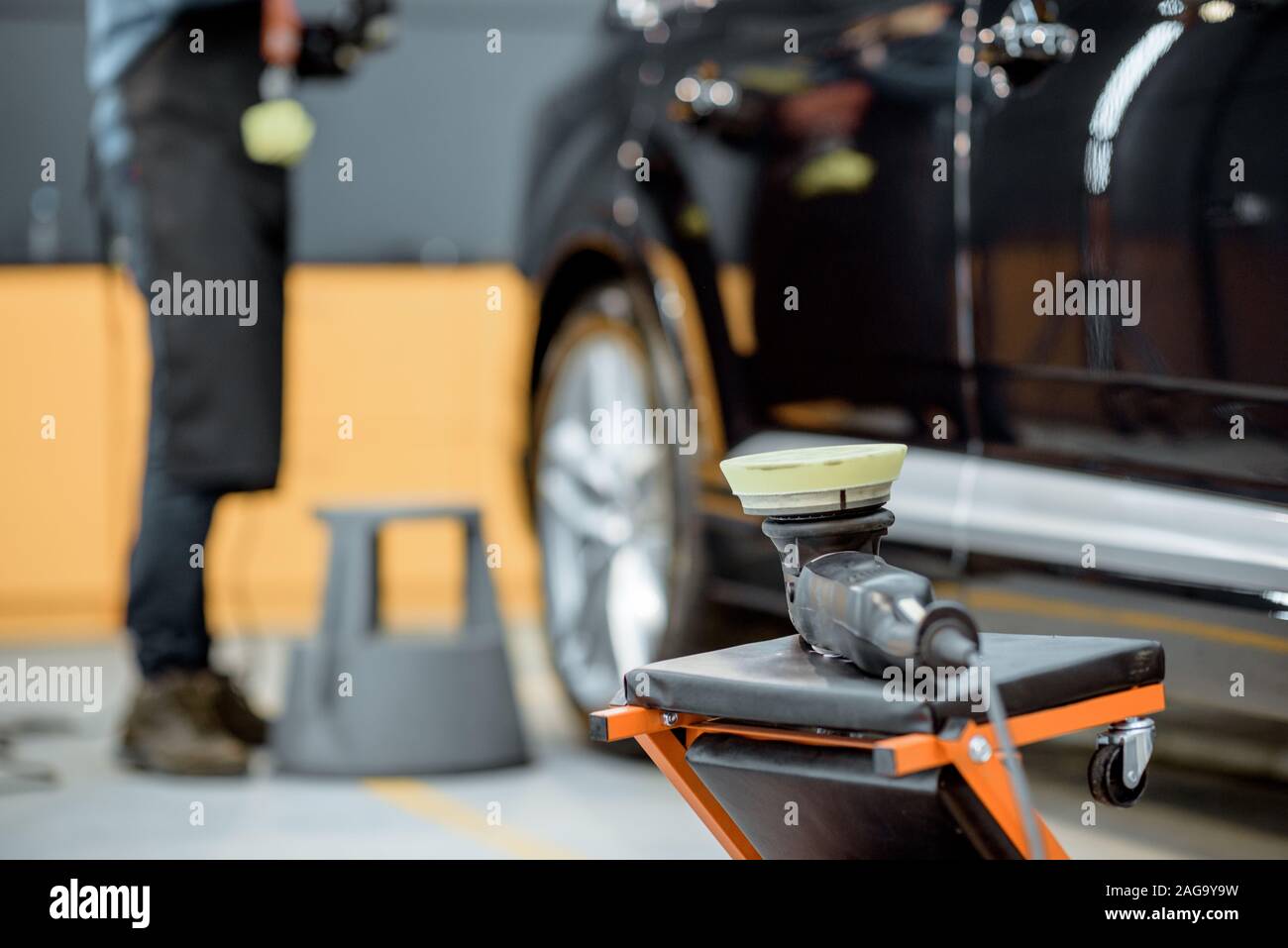 Professional equipment for vehicle body polishing at the car service with man on the background Stock Photo