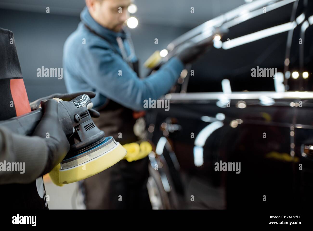 Workers holding grinder during a car polishing procedure at the service