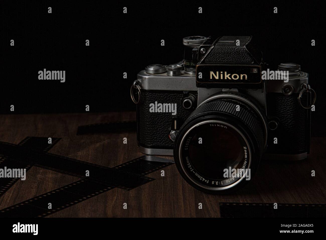 Vintage Nikon film camera on a wooden black background with film lens and camera shot in low key dark style Stock Photo