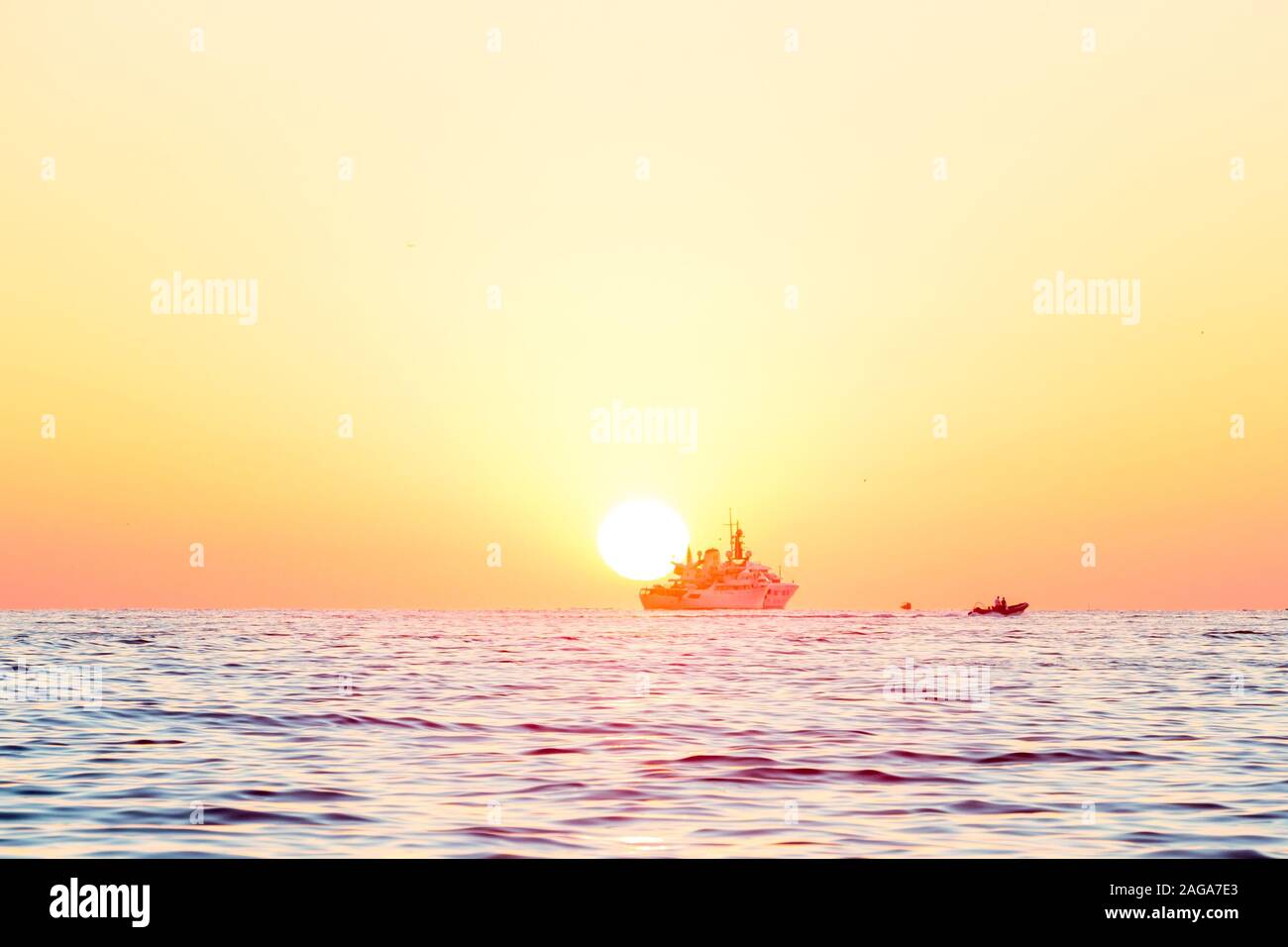 Breathtaking shot of the sunset over the sea and silhouettes of ships ...