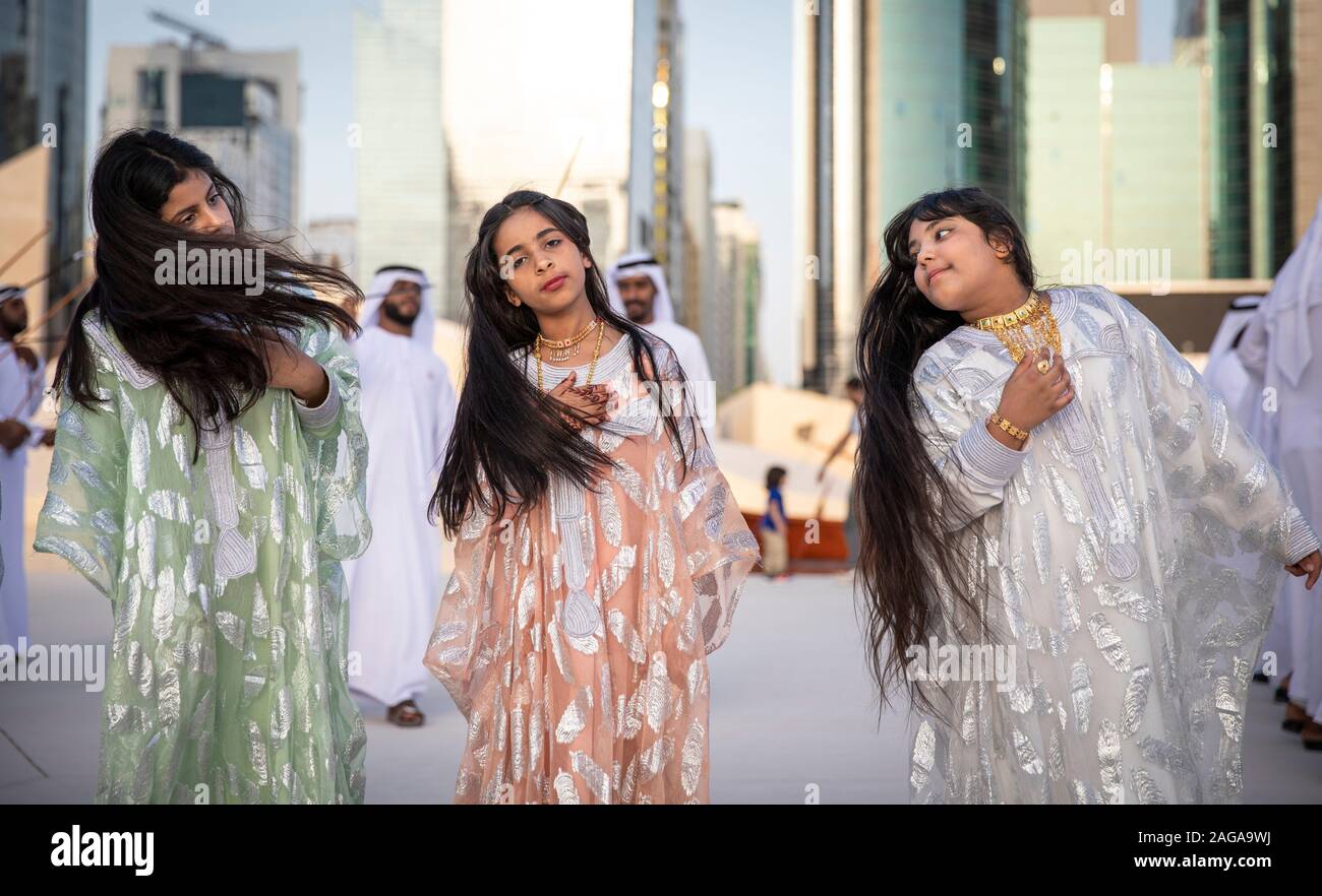 Abu Dabi, United Arab Emirates, 14th December 2019: ladies throwing their hair as men dance and sing at the background Stock Photo