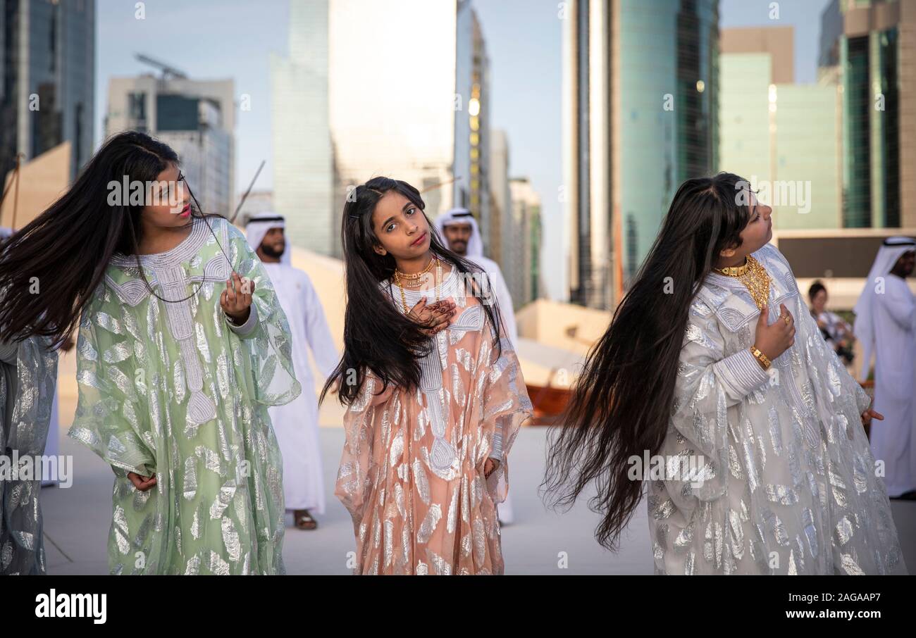 Abu Dabi, United Arab Emirates, 14th December 2019: ladies throwing their hair as men dance and sing at the background Stock Photo