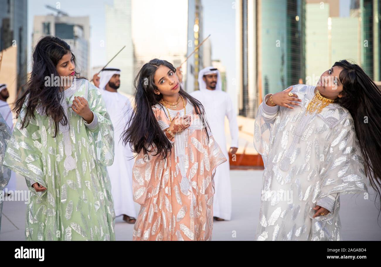 Abu Dabi, United Arab Emirates, 14th December 2019: ladies throwing their hair as men dance and sing at the background Stock Photo