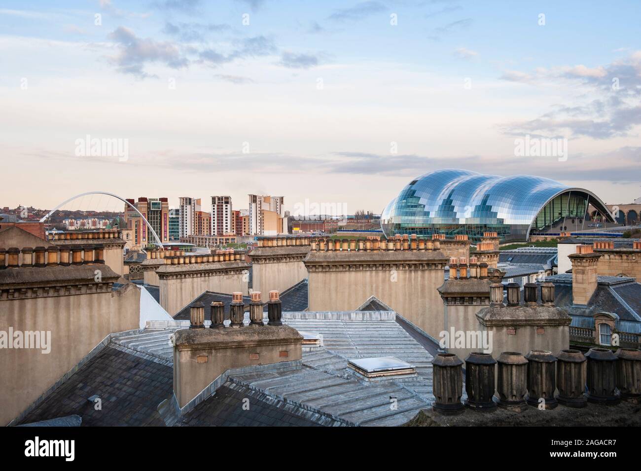 Roof tops and chimney pots of Newcastle upon Tyne with futuristic curving architecture of the Sage Gateshead in the distance. Stock Photo