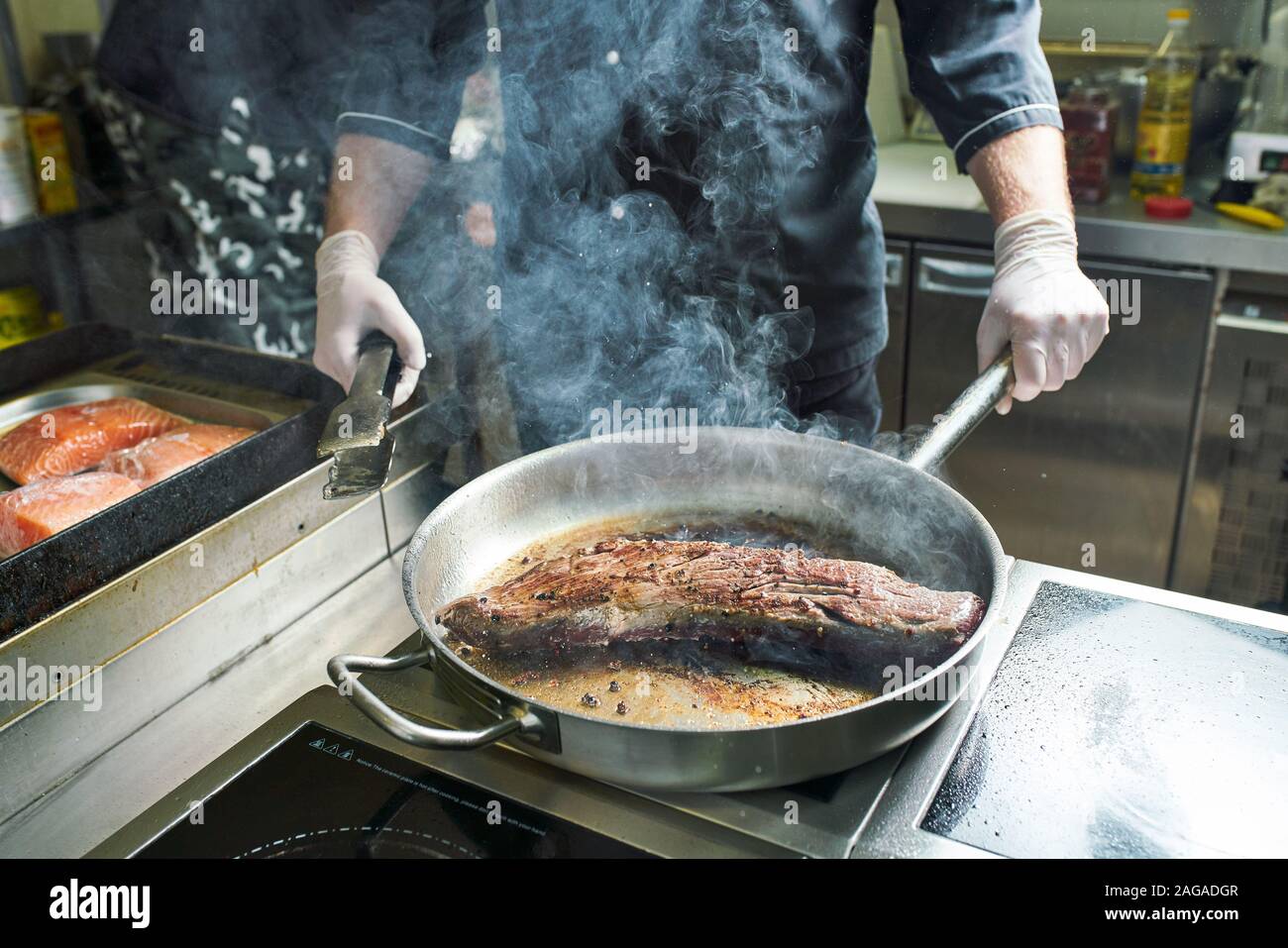 The chef works in the kitchen of the restaurant. Fresh meat roasted in ...