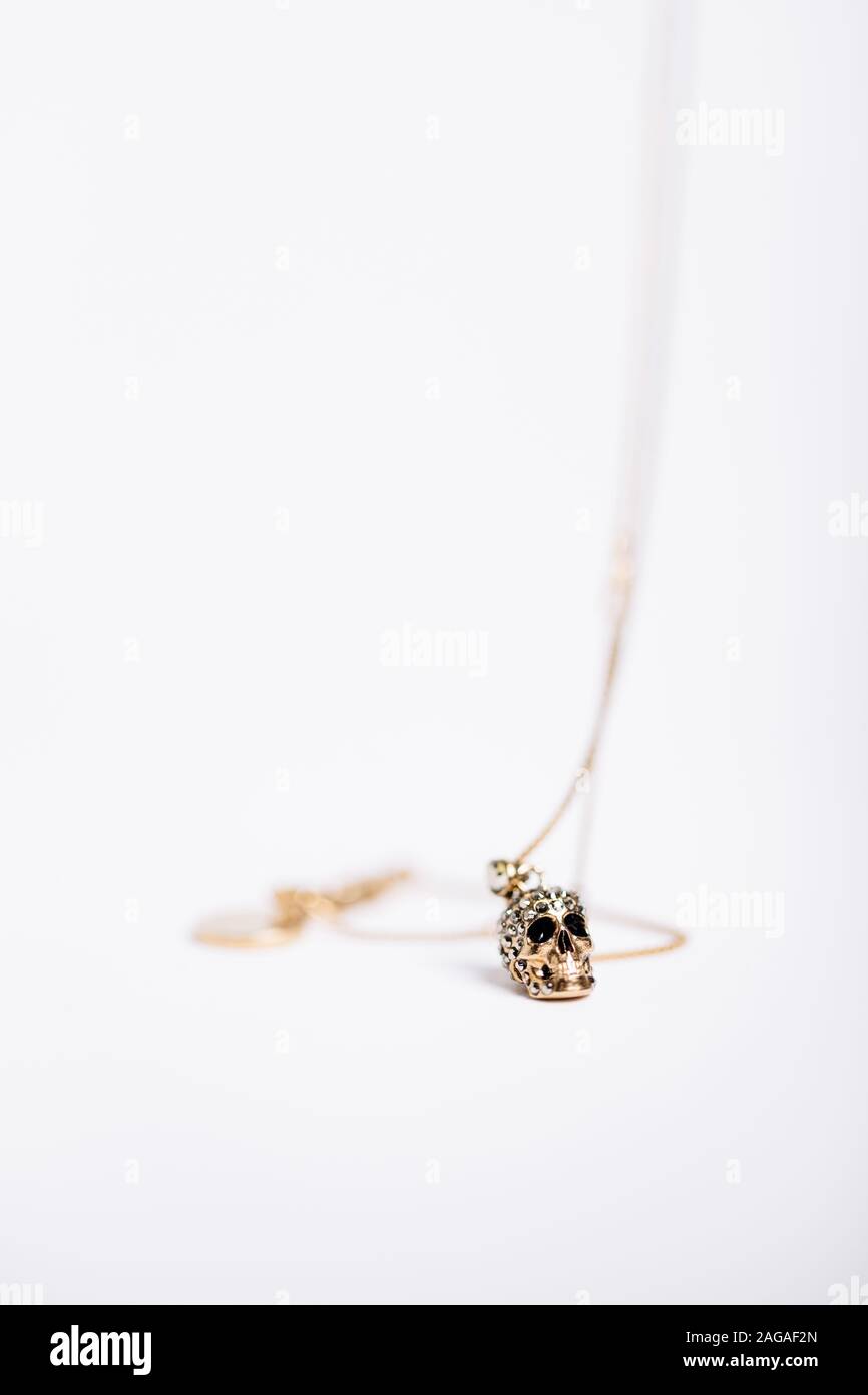 Vertical shot of a necklace with a skull-like charm on white background Stock Photo