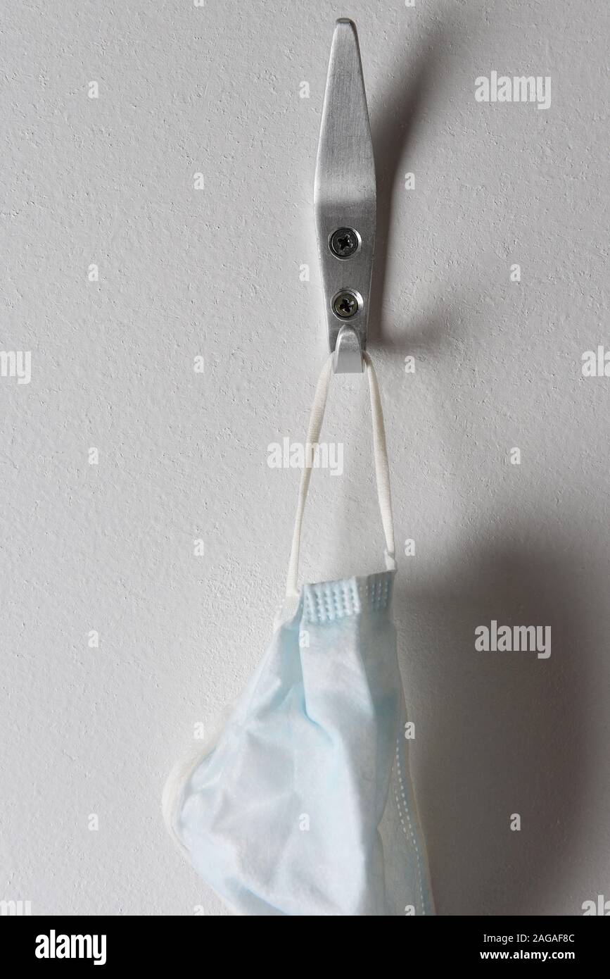 Closeup of a surgical mask hanging from a hook on a wall. Stock Photo