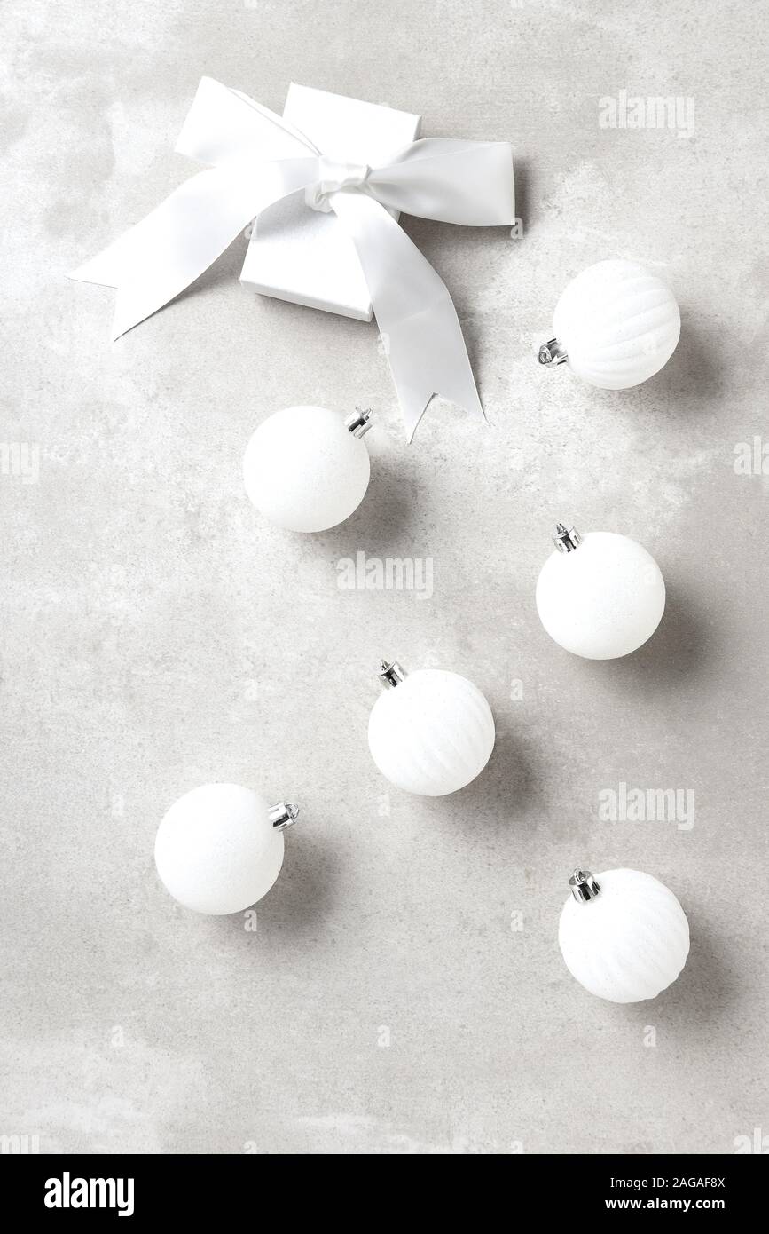 White Christmas Tree Ornaments on a light gray table top with a white gift box and bow. Stock Photo