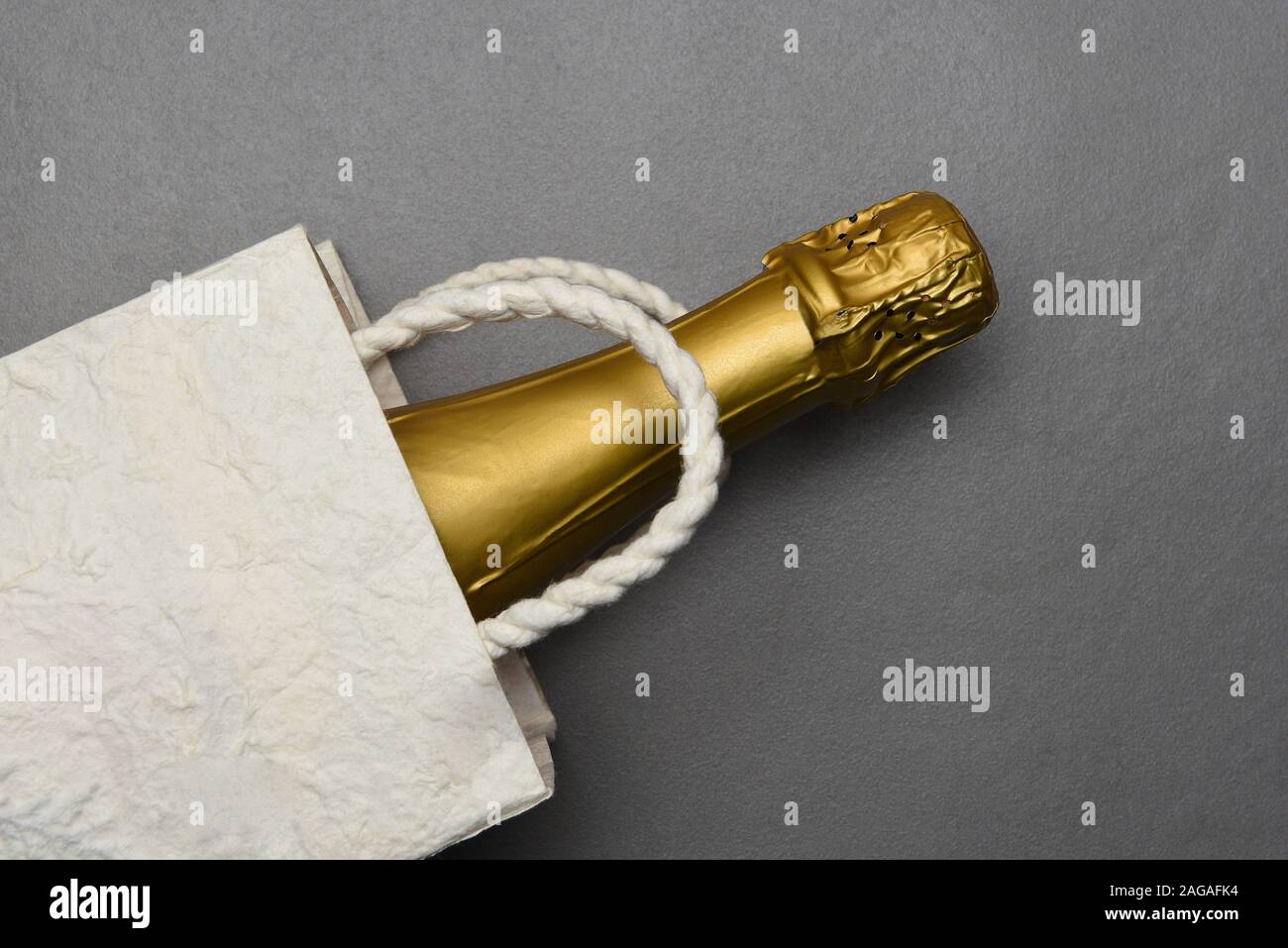 Champagne: Flat Lay Gift Bag with a bottle of sparkling wine on gray tile surface. Stock Photo