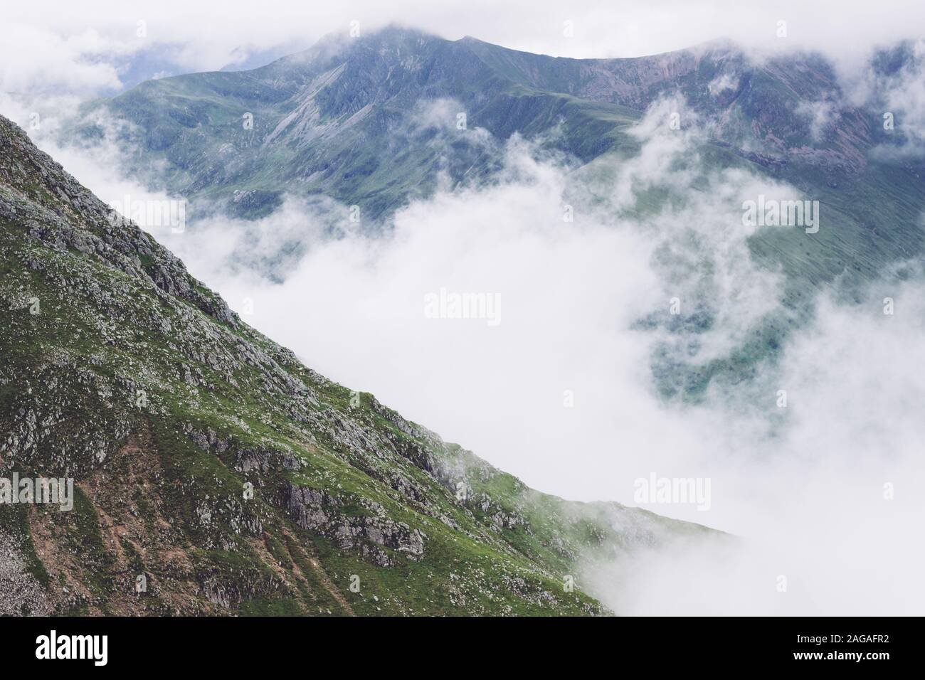 Scenery of smoke coming out of the mountains in the middle of a green view Stock Photo