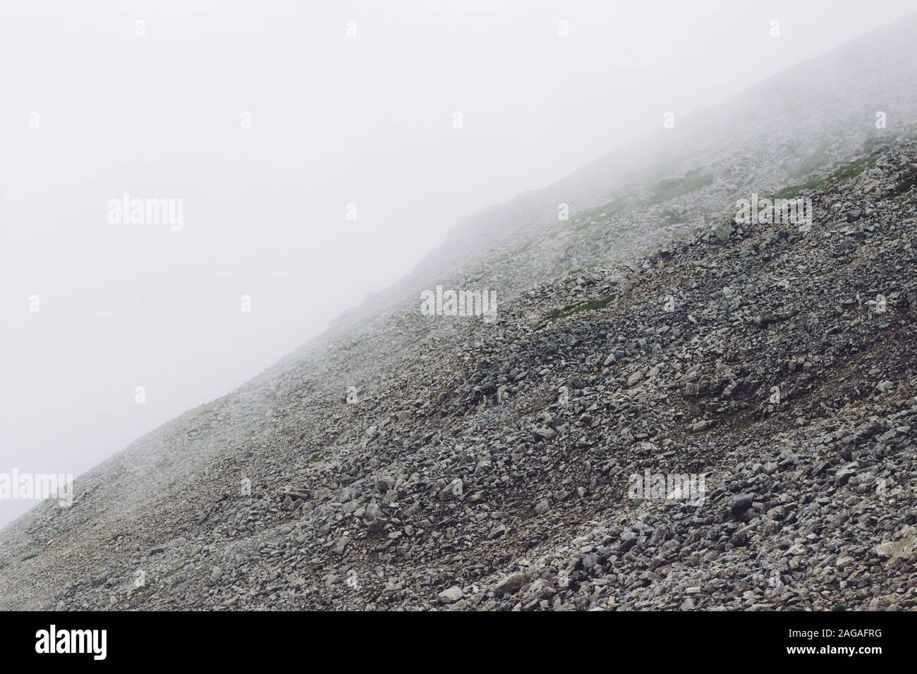 Low angle shot of smoke coming out of the mountains in the middle of a green scenery Stock Photo