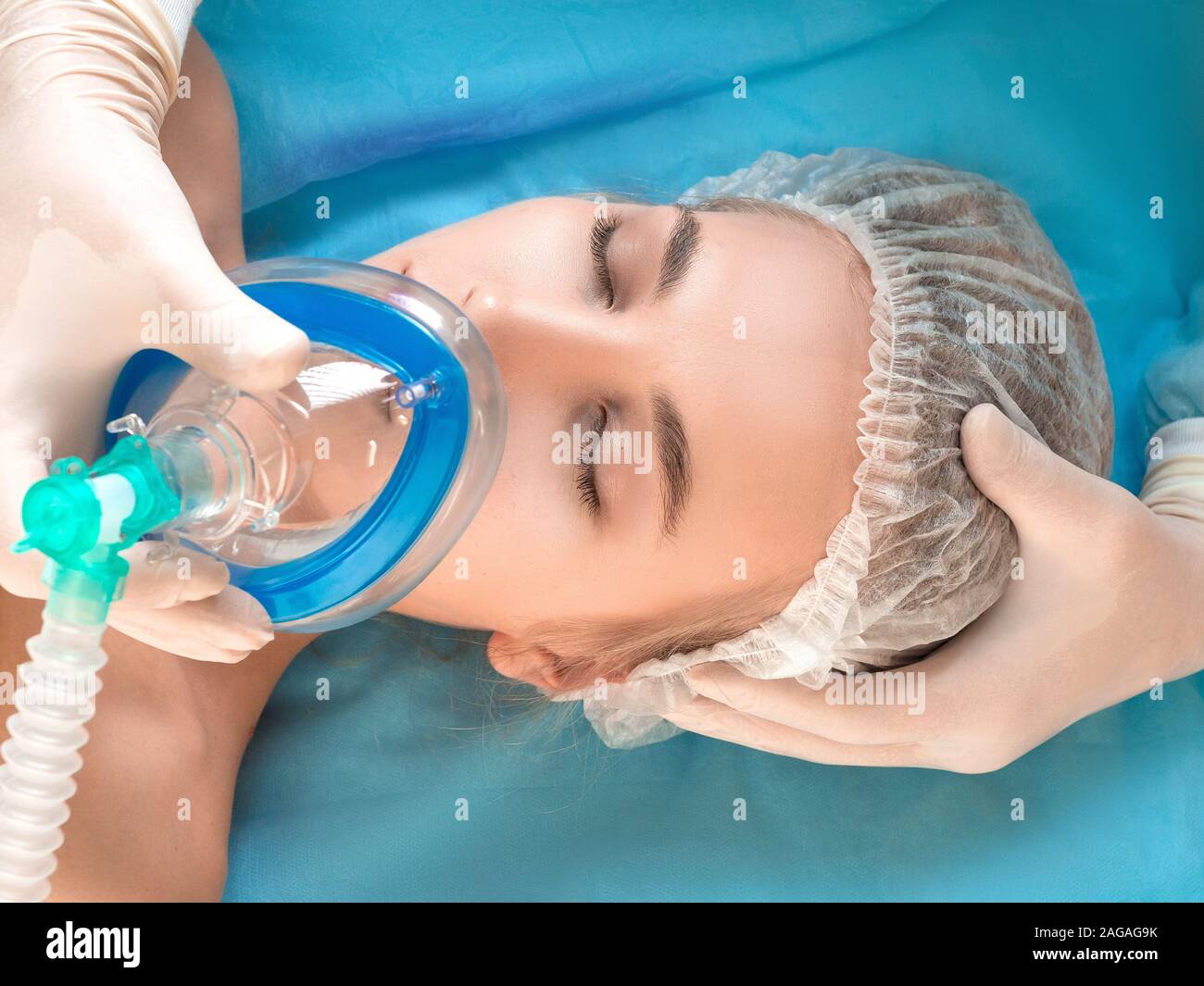 Beautiful patient receives nnaesthetic. Close up face of a patient and hands of a doctor. Stock Photo