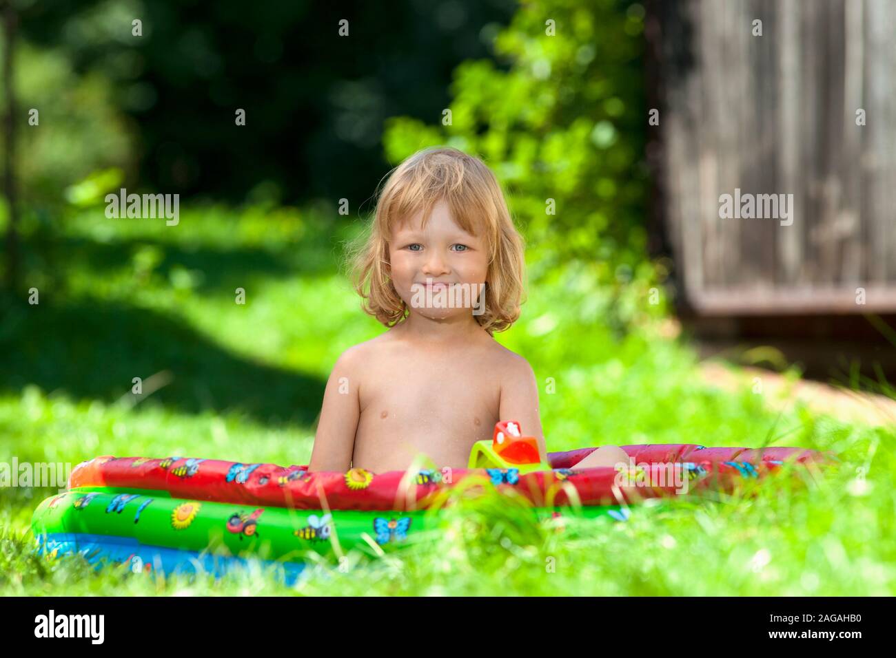 boy in inflatable pool in garden Stock Photo