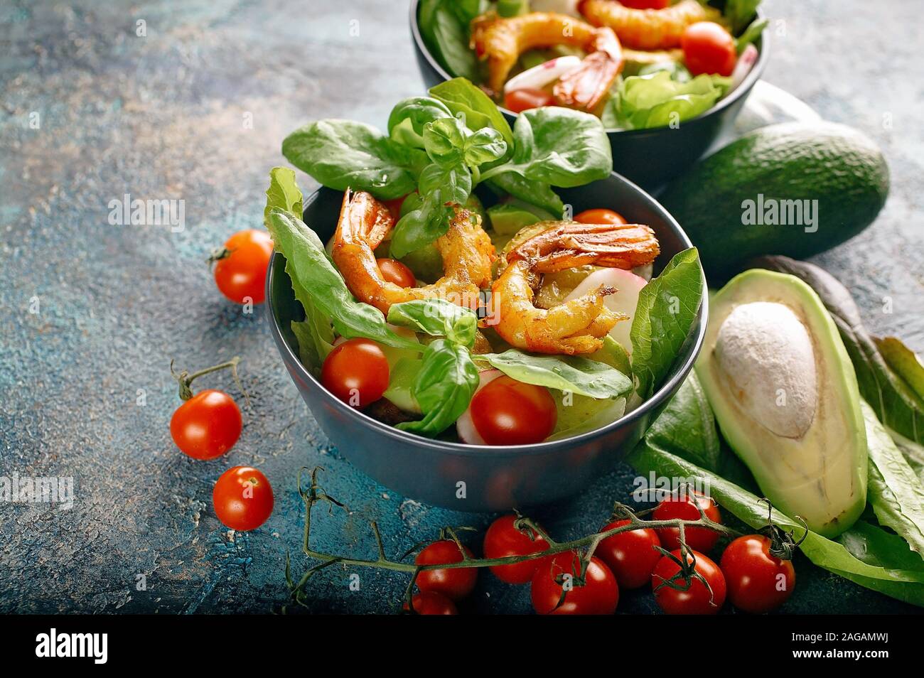 Close-up Appetizing salad with fried shrimp, avocado, cherry tomatoes, radish and basil. Tasty and healthy seafood. Stock Photo