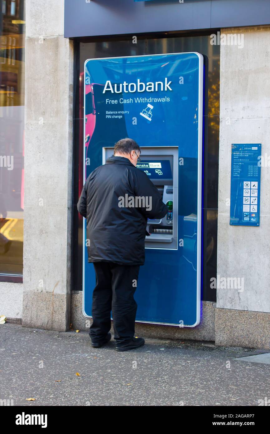 16 October 2019 A middle aged man operating an ATM in the busy Donegall Square West Belfast Northern Ireland. Stock Photo