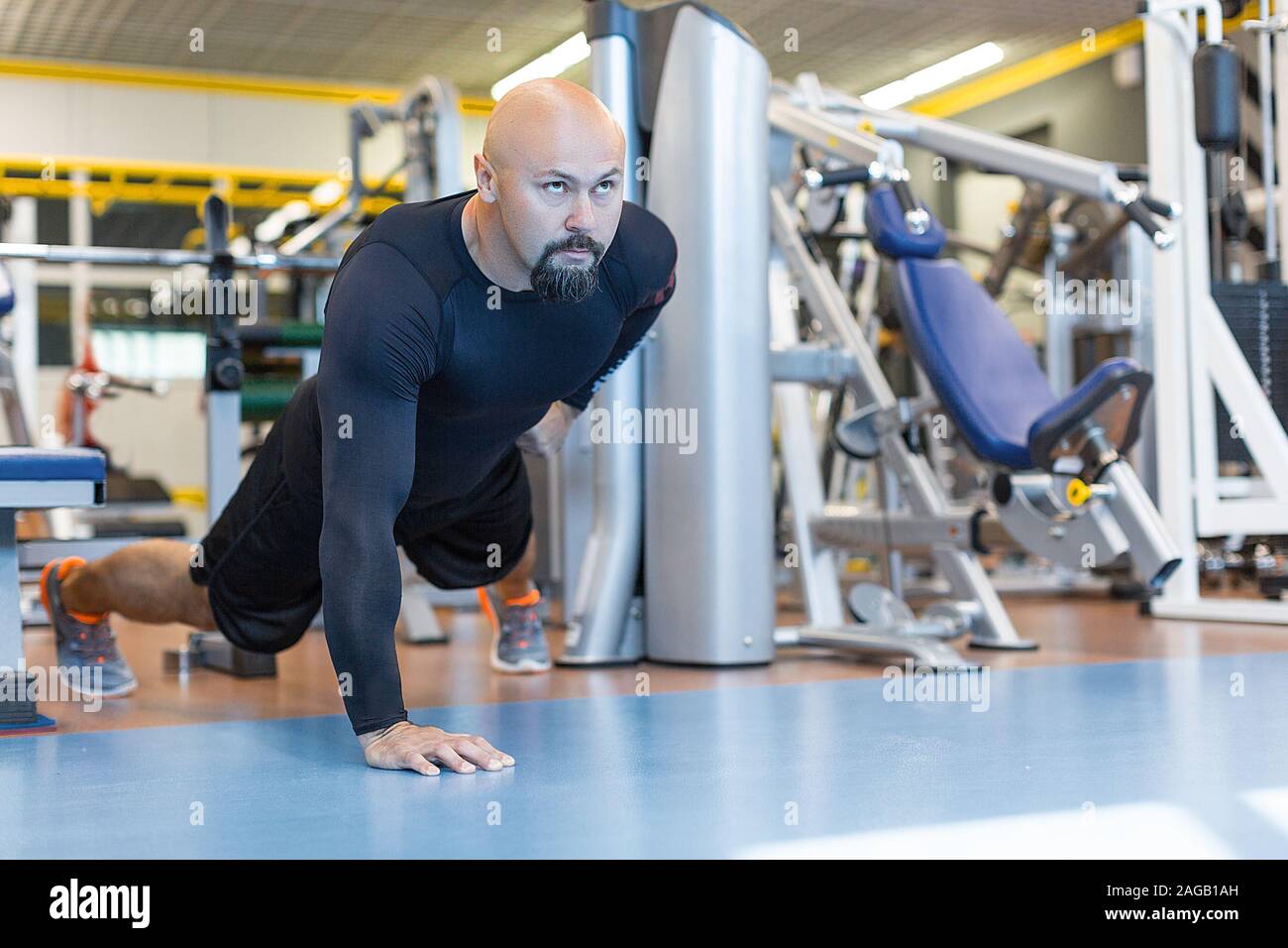 Brutal bearded man doing push ups exercise with one hand in fitness gym. Healty lifestyle concept Stock Photo