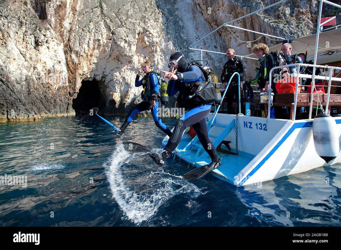 Scuba diver jumping from boat in the sea, rocky coast at Limni Keriou, Zakynthos island, Greece Stock Photo