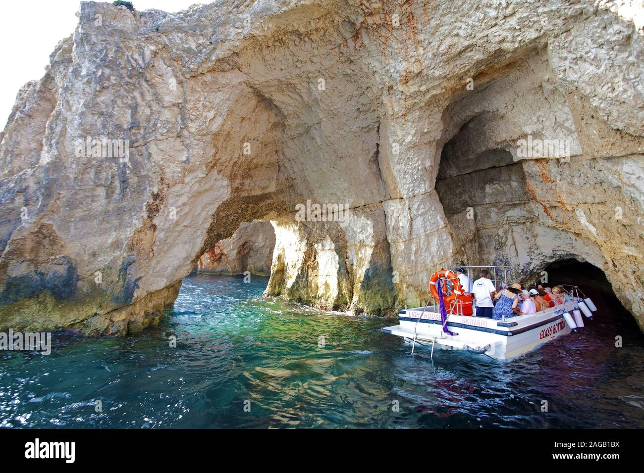 Pleasure boat with tourists entering the blue cave at Kap Skinari, Zakynthos island, Greece Stock Photo