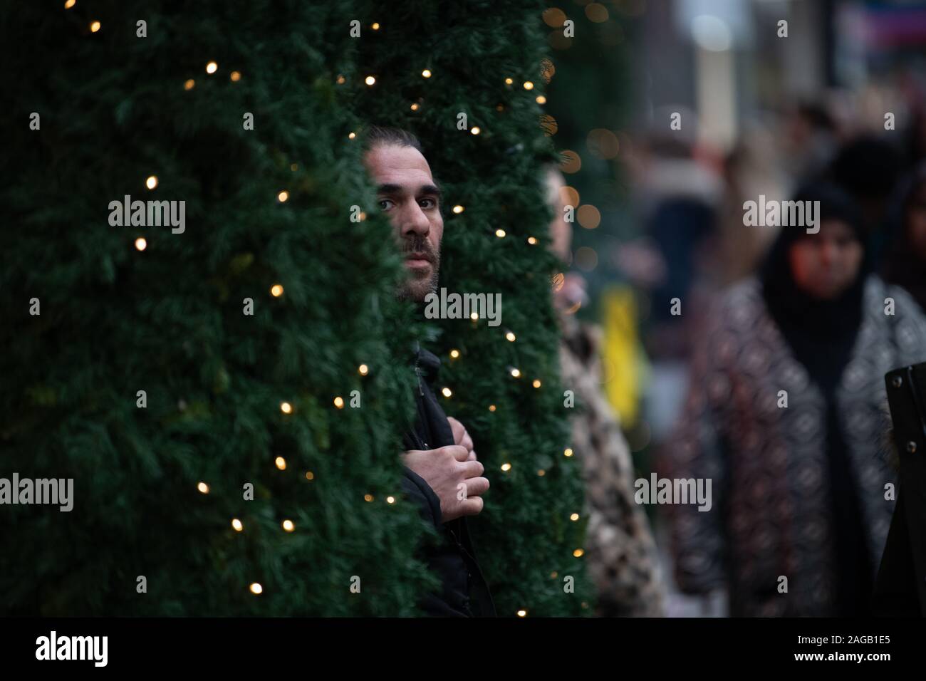 Mand posing for a photo between Christmas trees outside Selfridges Stock Photo